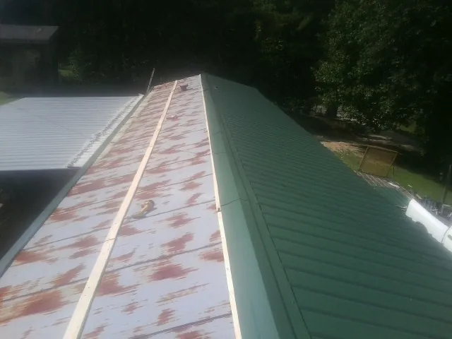 Old rusted panels beside newly installed green metal roofing — Wind Damage Roof Repair by Roofing Brothers in Silver Lake