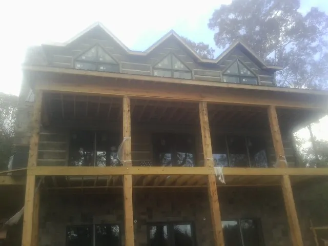 Dormers and porch framing on a large log home under construction — Roof Coating work by our crew in Silver Lake